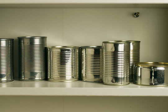 Aluminum tin cans stocked in a food cupboard shelf