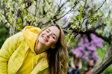 Smiling brunette woman at the spring park of violet and white lilac blur background