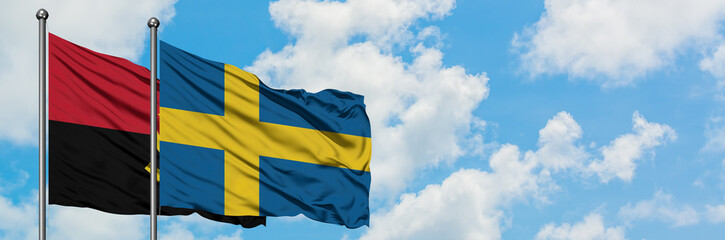 Angola and Sweden flag waving in the wind against white cloudy blue sky together. Diplomacy concept, international relations.