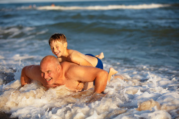 Dad and his son go in for sports on the seashore. A man is pushing up in water. Active holiday on the beach.Sports And Fitness Concept