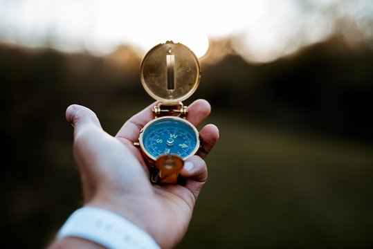 Closeup shot of a person holding a compass with a blurred background