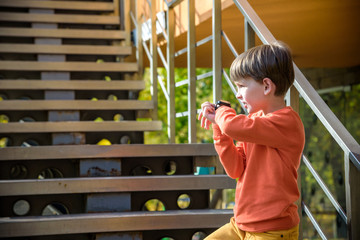 Photo of the boy looking at a smart watch. Children and modern technology. Kid calling to his...