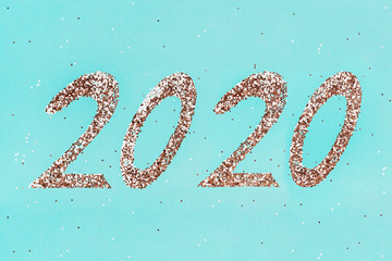 Golden sparkles shaped 2020 on green mint background.