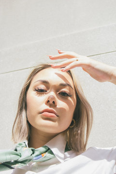 Low angle view of young woman shielding her eyes from sunlight