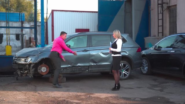 A man in a car service agrees repair with a young woman agent. Inspection of the car after an accident. Conversation with an insurance expert. Compensation for losses after an accident.