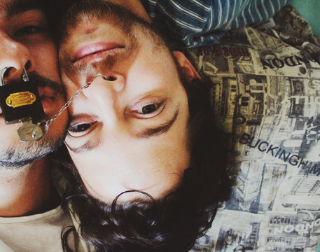 Couple chained together with lock and key in septum piercing