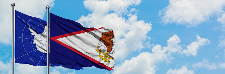 Antarctica and American Samoa flag waving in the wind against white cloudy blue sky together....
