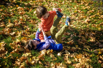 Two boys fighting outdoors. Friends wrestling in summer park. Siblings rivalry. Aggressive kid hold...