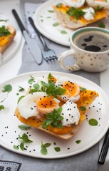 Bruschetta with pumpkin puree, boiled eggs, fresh basil and cream cheese on grey linen textile. Cup of coffee on the background. 