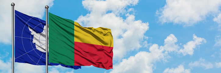 Antarctica and Benin flag waving in the wind against white cloudy blue sky together. Diplomacy concept, international relations.