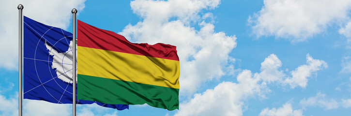 Antarctica and Bolivia flag waving in the wind against white cloudy blue sky together. Diplomacy concept, international relations.