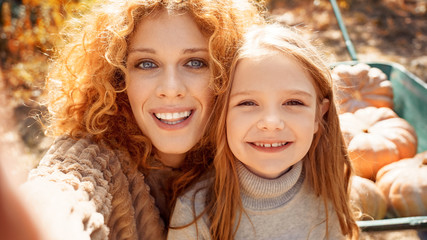 Fototapeta premium Young adult mother and daughter looking at carved pumpkin with smoke