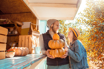 Halloween Preparaton Concept. Young couple decorating house with pumpkins looking at each other...