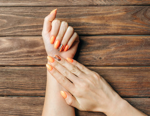 Young female hands with beautiful manicure of orange color.