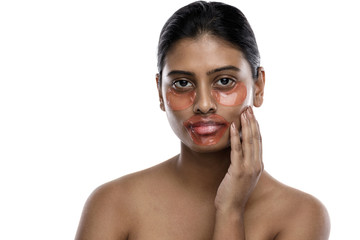 Beautiful Indian woman with hydrating eye patches and lip mask on her face