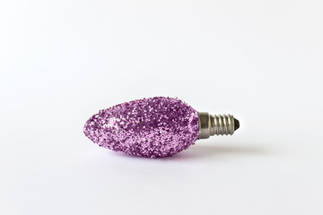 Light bulb covered with pink glitter on white backgound