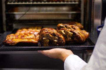 the cook takes out of the oven baked ruddy meat with a golden crispy crust