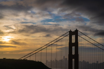 Golden Gate bridge in silhouette under a cloudy sky at sunrise 