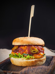 Burger with cheese, tomato, jalapeno, lettuce on the board