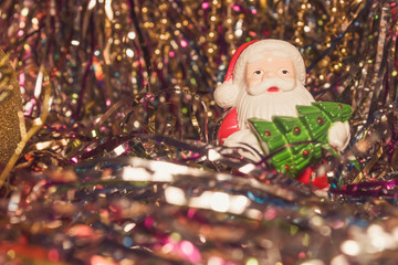 Santa Claus toy with Christmas tree in hands. Santa Claus with a green Christmas tree on a shiny colored tinsel. Father Christmas for the new year.