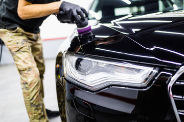 Obraz na płótnie Canvas Car detailing - Worker with orbital polisher in auto repair shop.