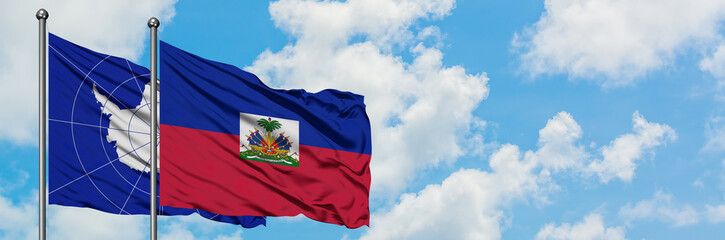 Naklejka premium Antarctica and Haiti flag waving in the wind against white cloudy blue sky together. Diplomacy concept, international relations.