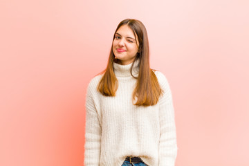 young pretty woman looking happy and friendly, smiling and winking an eye at you with a positive...