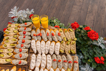 restaurant patio table sandwiches with hummus and vegetable orange juice, flower bed exterior yard decoration and wooden deck floor unfocused background top view poster picture with empty copy space