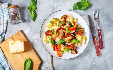 Pasta with grilled vegetables - zucchini, eggplant, pepper ant tomato on concrete background.