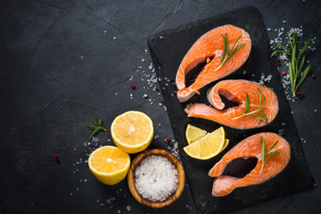 Raw salmon steak on black top view.