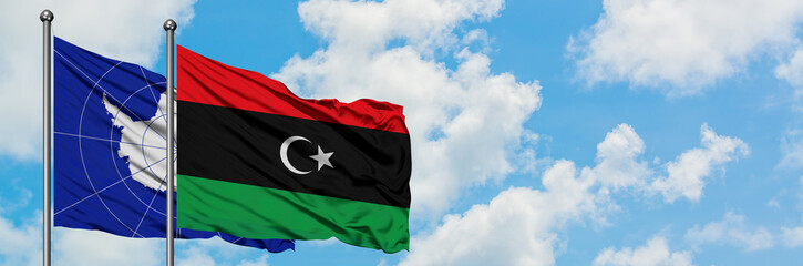 Antarctica and Libya flag waving in the wind against white cloudy blue sky together. Diplomacy concept, international relations.
