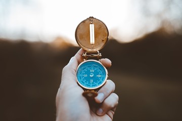 Closeup shot of a person holding a compass with a burred background © Ben White/Wirestock