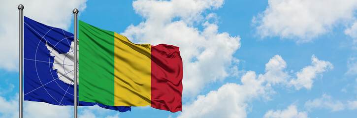Obraz premium Antarctica and Mali flag waving in the wind against white cloudy blue sky together. Diplomacy concept, international relations.