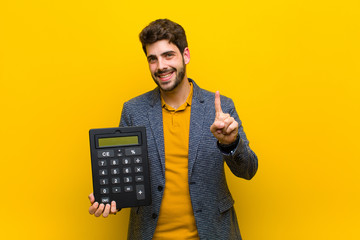 young handsome man with a calculator against orange background