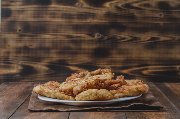 Fried crispy nuggets in a white bowl on a wooden background. Copyspace. Chicken strips