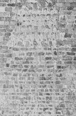 Old and aged brick wall with some weathered plastering. High resolution full frame textured background in black and white.