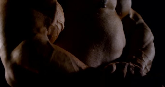 slow motion close up of a muscular male bodybuilder straining his arm muscles
