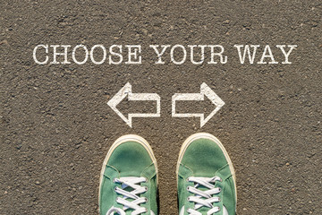 photo on top of the sneakers and the inscription choose your way on the asphalt, the concept of free choice, direction of movement, the philosophical question of life