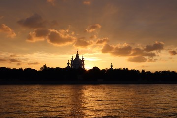 Fototapeta na wymiar orange sunset over the river with dark church silhouetted on the