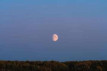 Alaskan mountains with half moon and pink skies after sunset during blue hour