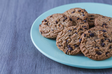 Some homemade chocolate cookies on a green plate on wooden table.