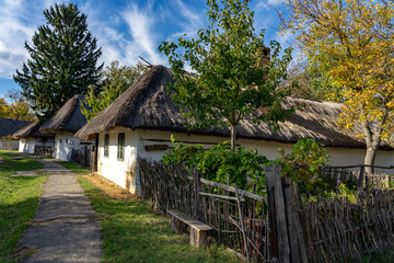 Fototapeta na wymiar Historical old hungarian village with straw roof houses and a bench next to the street in Szombahely Hungary