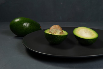 Fresh, raw avocado sliced on a black plate