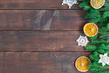 New year composition on wooden background with green pine branches, crochet snowflakes and dry oranges. Image with copy space, top view