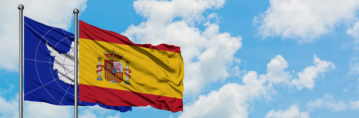 Fototapeta premium Antarctica and Spain flag waving in the wind against white cloudy blue sky together. Diplomacy concept, international relations.