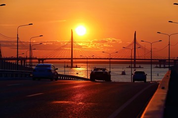 Orange sunset over the highway with a bridge over the river and