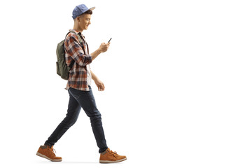 Young guy with a backpack and cap walking and looking at his mobile phone