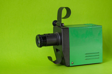 Vintage old projector for viewing filmstrips on a green background. Retro style