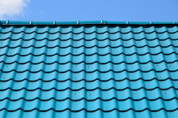 Turquoise metal tiles on roof of the house. Modern roofing materials