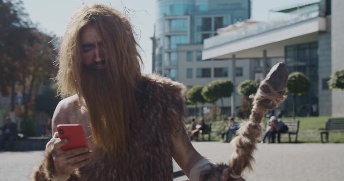 Serious neanderthal of hunter-gatherers discovering modern device use mobile phone in modern city civilization cro-magnon device evolution future homo sapiens human modern caveman ancient slow motion